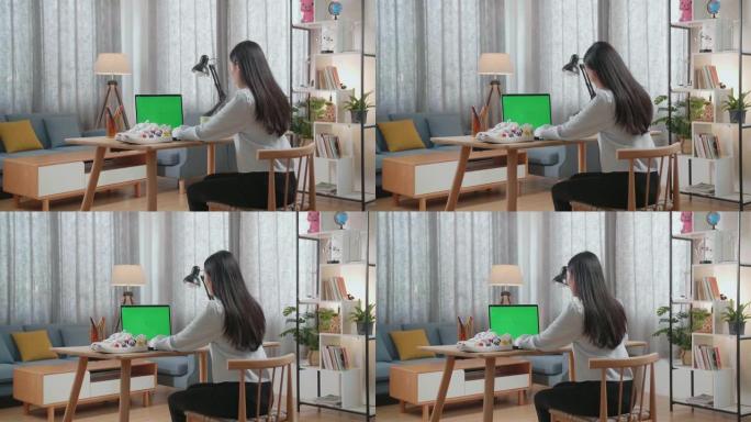 亚洲女鞋设计师在家中使用带有模拟绿屏的笔记本电脑