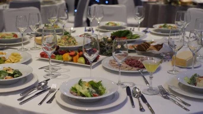 派对或婚宴用桌子的跟踪镜头。餐厅奢华优雅的晚餐。咖啡馆里的盘子、玻璃杯和白色桌布桌子