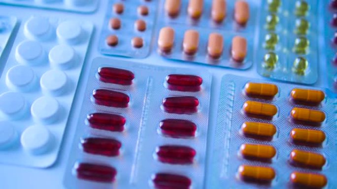 许多彩色片剂中的药物水泡躺在桌子上，大量选择抗菌，抗组胺药和抗病毒药物，为寒冷的季节做准备