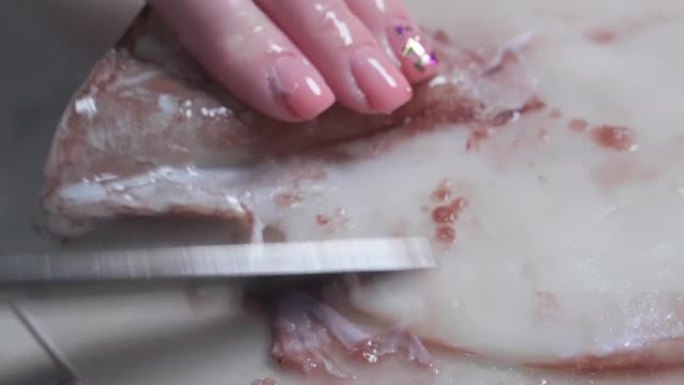 在煮鱿鱼之前，用刀将鱿鱼的皮肤剥去。