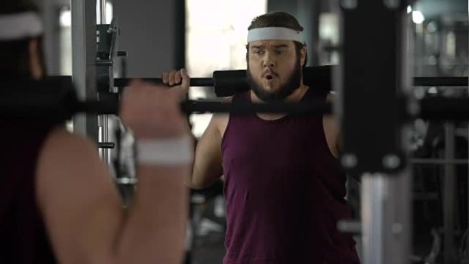 肥胖男子在健身房、健身锻炼、运动中几乎没有用杠铃锻炼