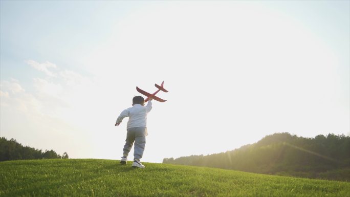 拿着飞机模型奔跑的小男孩背影欢乐童年时光