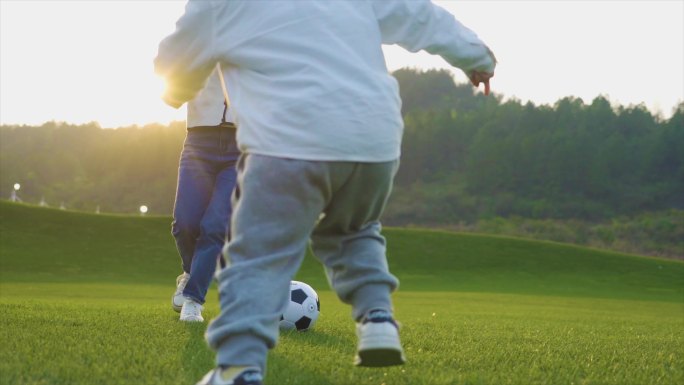小男孩和妈妈在草地嬉戏踢足球温馨家庭父母