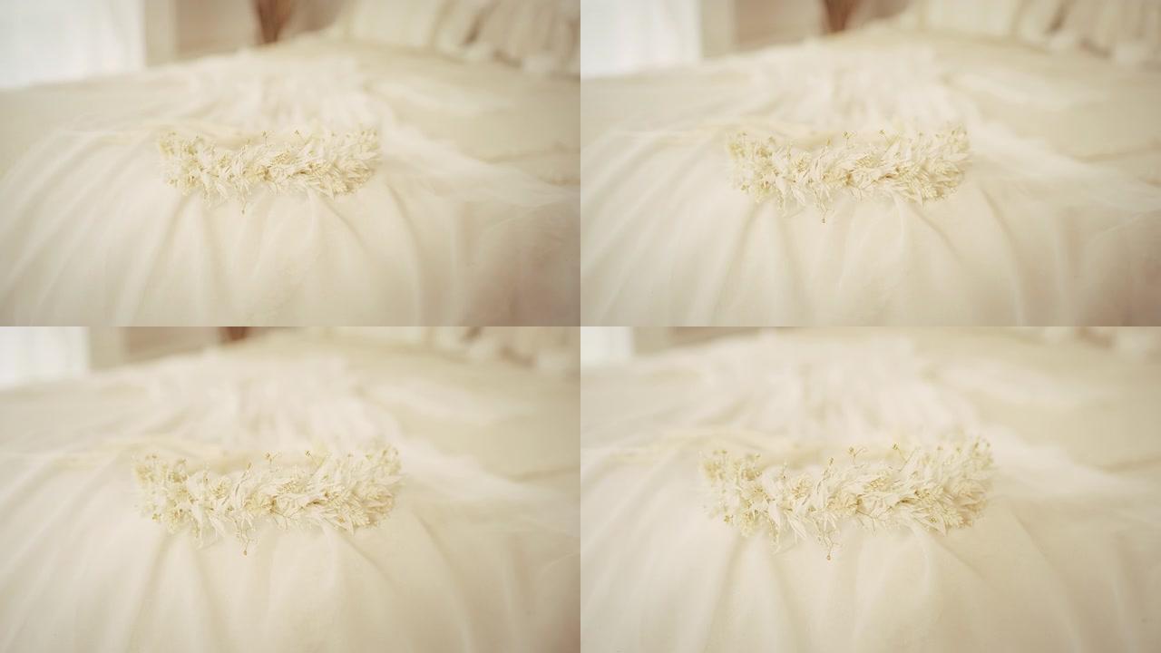 在婚纱上躺着干花的白色花环。(特写)。