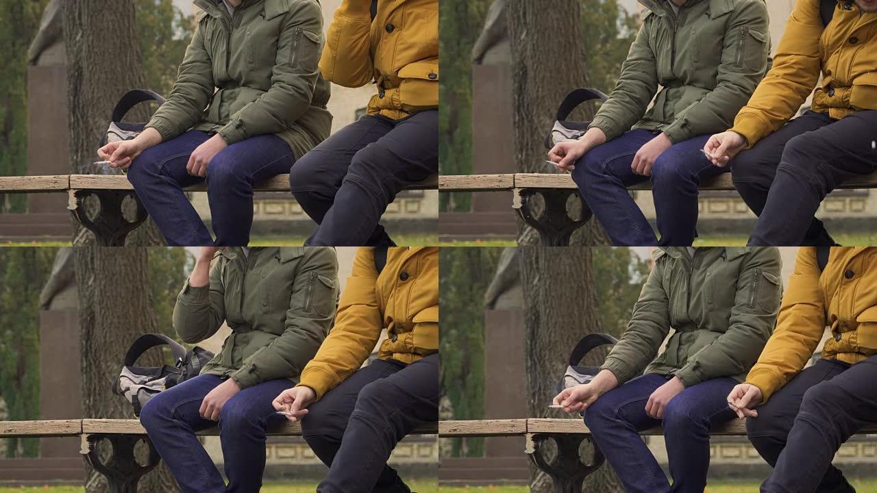 学生坐在公园的长凳上吸烟