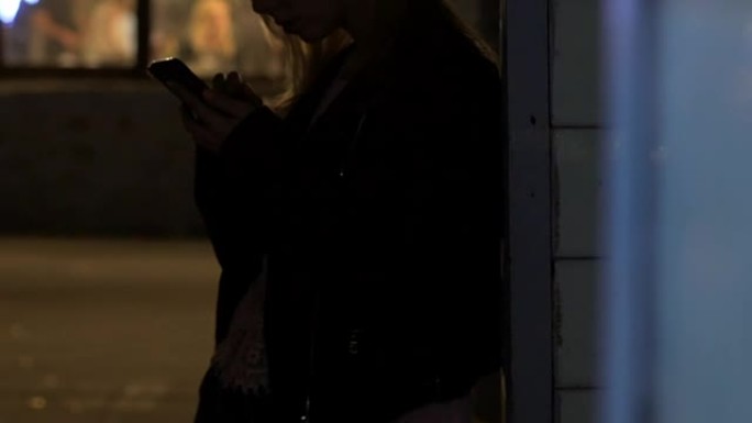 孤独女孩的剪影在户外清新，在智能手机上刷照片