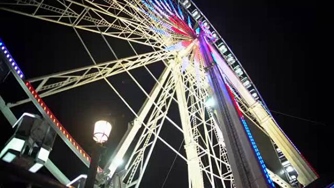 游乐园的欢乐之夜，彩色照明巨型摩天轮旋转