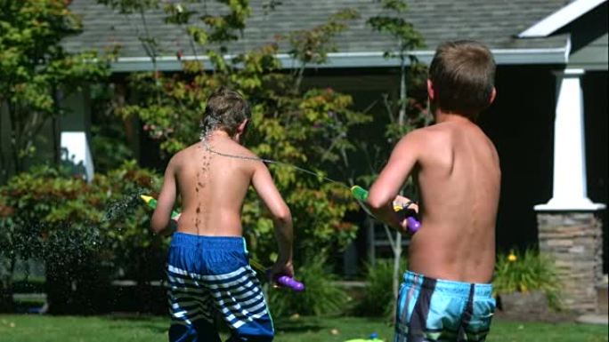 两个小男孩用水枪慢动作打架。