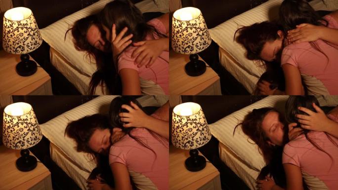 小女孩拥抱和亲吻痛苦的女人躺在床上的枕头上，在卧室里哭泣。女儿帮助母亲冷静下来。