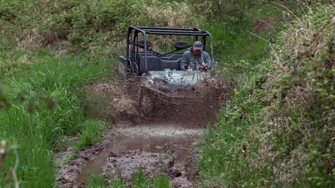 男子驾驶全地形车穿过泥泞，慢动作