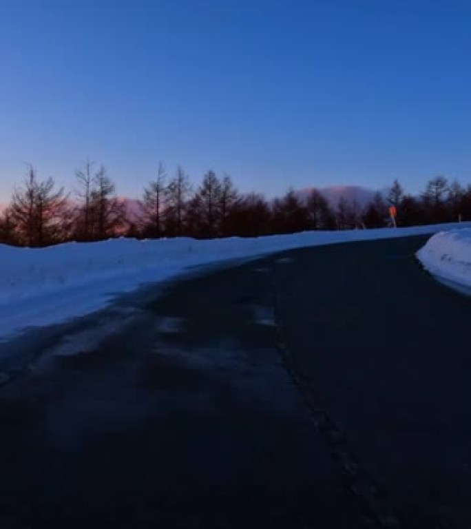 黄昏时在雪山路上行驶。