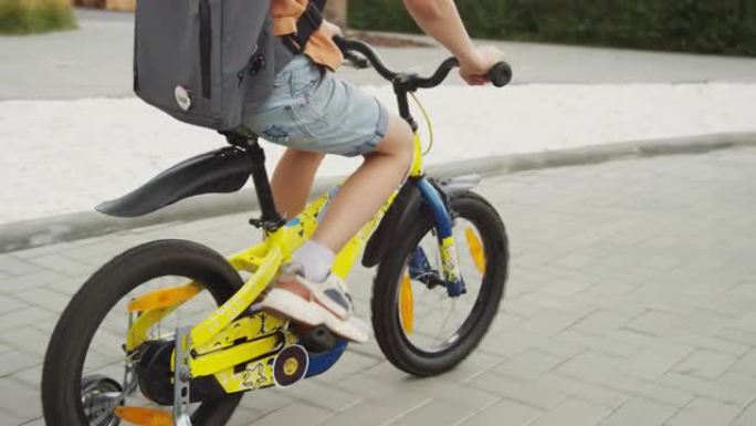 匿名儿童骑着带训练轮的自行车