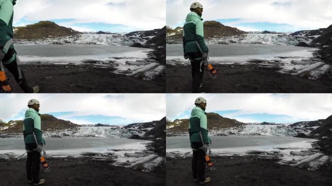 带有斧头和冰爪的女性徒步旅行者望着冰川