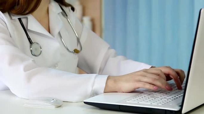 女医生在笔记本电脑上浏览页面，打字，咨询病人