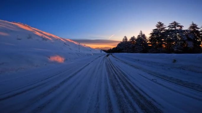 黄昏时在雪山路上行驶。