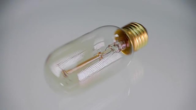 爱迪生的电灯旋转并在光滑的白色发光表面上滚动