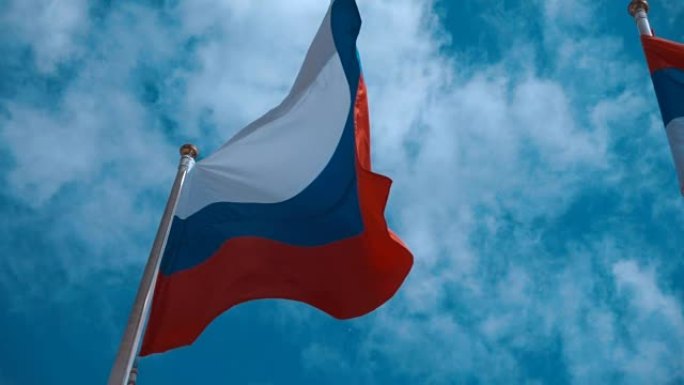 旗杆上的俄罗斯国旗在风中挥舞着蓝天，云彩