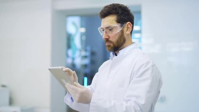 集中成熟的科学家，穿着白色外套，戴着防护眼镜和手套，手持数字平板电脑，从事研究科学工作