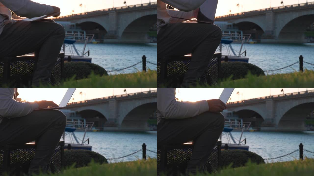 男子在滨水区附近使用笔记本电脑