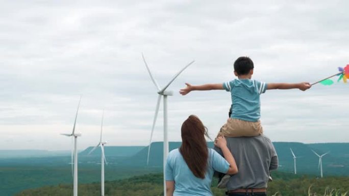 进步幸福家庭在风力发电机场享受时光的概念