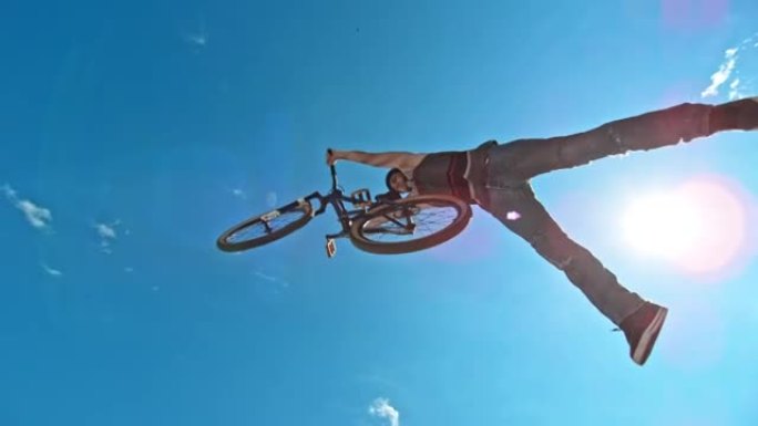 SLO MO男骑自行车的人在阳光下用他的DJ自行车做超人把戏