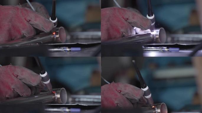 剪影，焊工的手在保护手套工作与金属钢和铁使用焊接机，明亮的火花和闪光在极端。工人在制造厂焊接金属。

