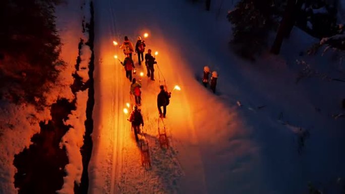 一群人在晚上用灯笼拉着雪橇在雪路上