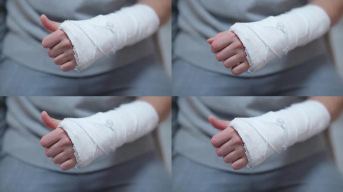 手臂上有石膏的人。骨折时手自我运动的困难。断指手的痛苦沉重动作特写。