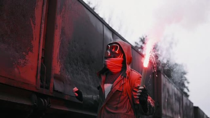 戴着防毒面具的蒙面男子，在被毁的火车站的马车上，手里拿着燃烧的信号火