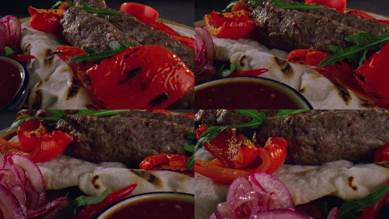 皮塔饼上的热烤肉串放在洋葱木盘子上。红甜椒、酱汁和西红柿