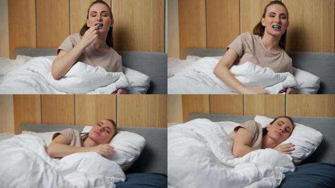 一个有魅力的女人在晚上睡觉前使用多功能训练器。它们有助于对准正在生长的牙齿并纠正咬合。纠正舌头的位置
