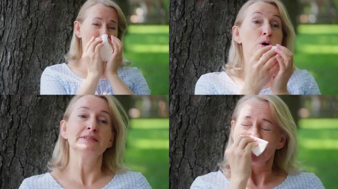 50多岁的金发女人在夏季公园休息时打喷嚏，过敏，鼻炎