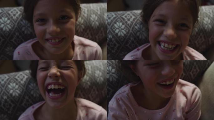 一个可爱的小女孩看着镜头，一边发痒一边笑的肖像。穿着睡衣的快乐顽皮的女孩子在睡觉前和父母玩耍，玩得开