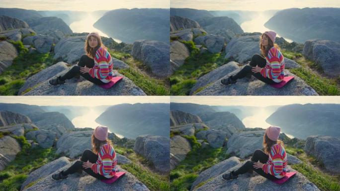 女人坐在Lysefjorden的背景下的山上