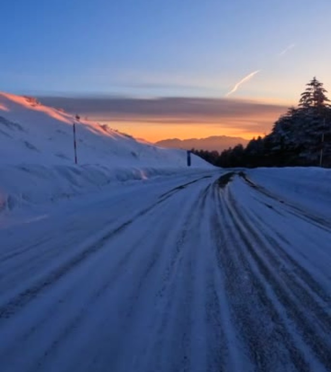 黄昏时在雪山路上行驶。