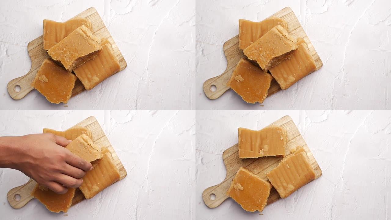 在桌子上手工挑选一个粗放的传统甘蔗方块