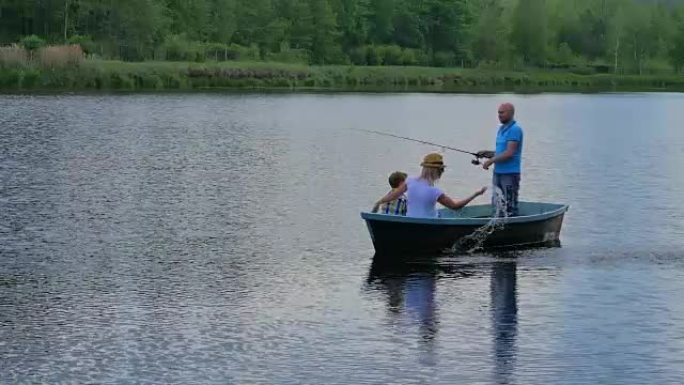 母亲，父亲和小儿子在湖上的船上放松