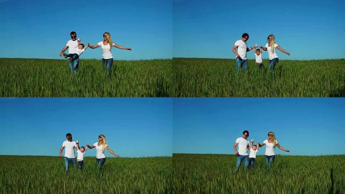 幸福的家庭: 父亲，母亲和儿子，穿着白色t恤在田野里奔跑
