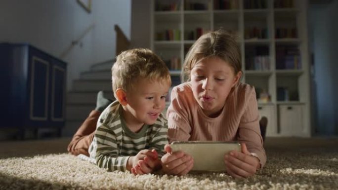 一个小男孩蹒跚学步和他的妹妹在智能手机上观看视频的肖像。快乐的兄弟姐妹使用电话，与儿童游戏一起唱歌。