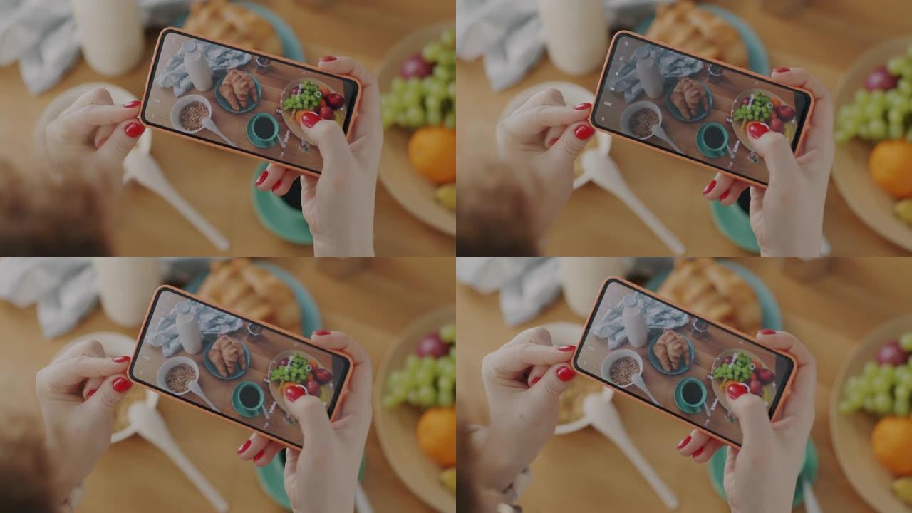 使用智能手机拍摄食物平放在厨房桌子上的女性手的特写