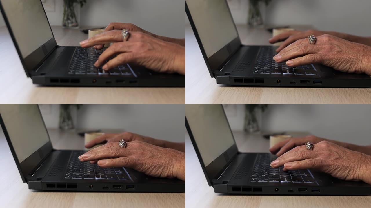 一个老女人在笔记本电脑上打字的手的特写。