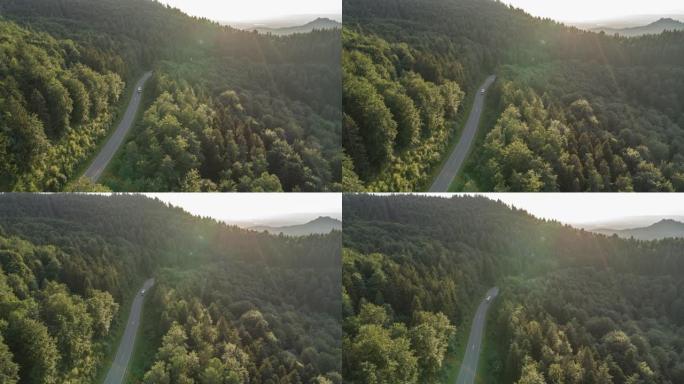 在日落时，一辆露营车在森林道路上行驶的空中无人机拍摄