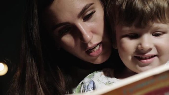妈妈和宝宝正在看书。正在看书，睡前阅读的妈妈和孩子的脸的特写视图。前视图和慢动作视图