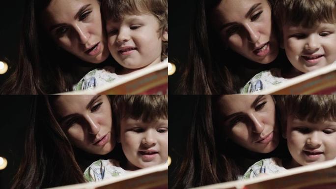 妈妈和宝宝正在看书。正在看书，睡前阅读的妈妈和孩子的脸的特写视图。前视图和慢动作视图