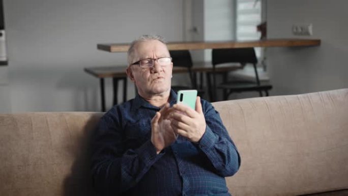老人在家，用智能手机打字。一名头发花白、戴眼镜的男子用手机上的wi-fi和互联网进行通信和订购在线服