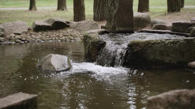 水流，城市公园里有苔藓的圆形混凝土碗瀑布。