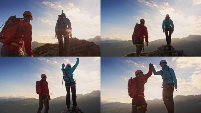 女登山者在山顶上举手并与登山者一起庆祝