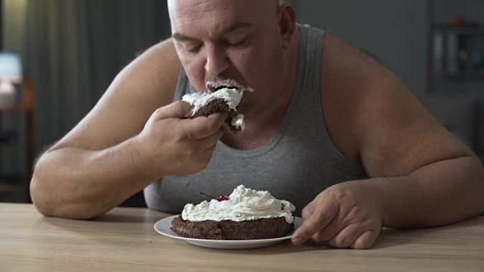 肥胖的人贪婪而迅速地吃鲜奶油蛋糕，上瘾