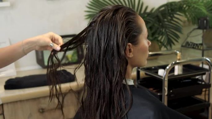 美发师在客户的头发上喷洒喷雾剂。护发产品。