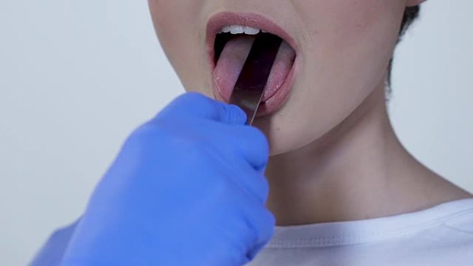 全科医生用医用压舌器检查患者的喉咙